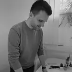 Colleague in a grey sweater at a table in a pink lit room
